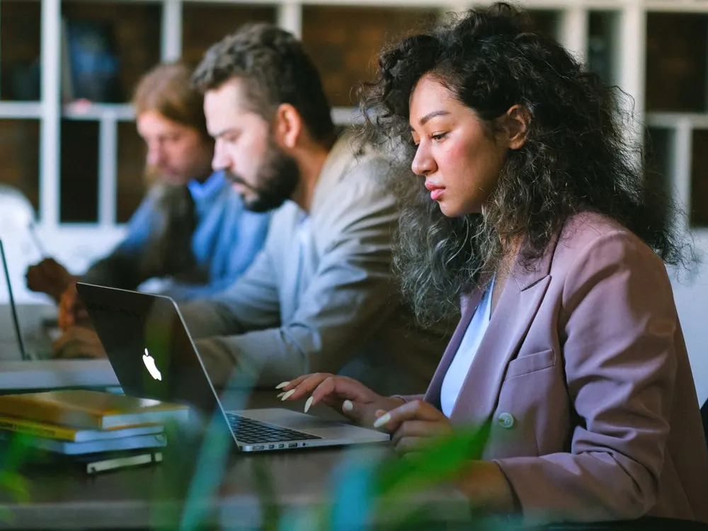 Person focused on their laptop at a shared workspace