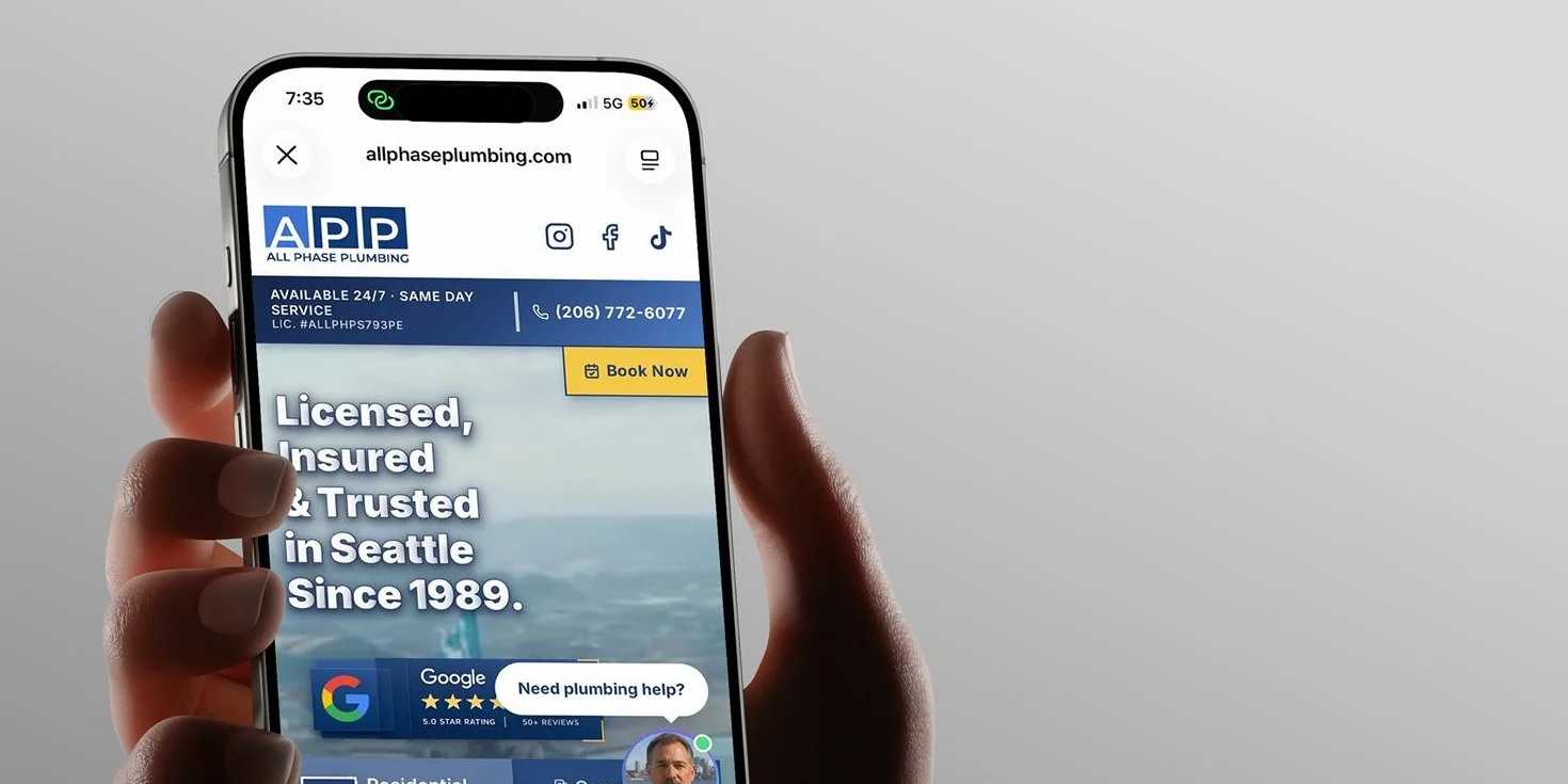 A hand holding a phone showing the new site's homepage